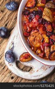 meat in plum sauce. meat stew in a sauce of autumn plums on a retro background