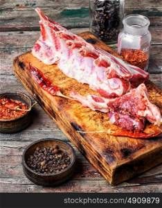 meat on rib. raw meat on the rib of lamb in hot spices on the kitchen board