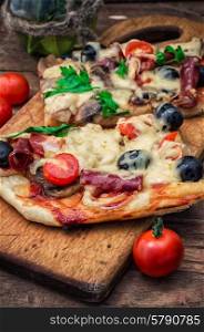 meat pizza made with salami,cheese,mushrooms,cherry tomatoes and olives.The image is tinted.Selective focus