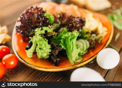 Meat salad in a bowl, knife, fork and pepperbox on wooden table, top view, nobody. Food preparation, cooking. Meat salad in a bowl on wooden table, top view