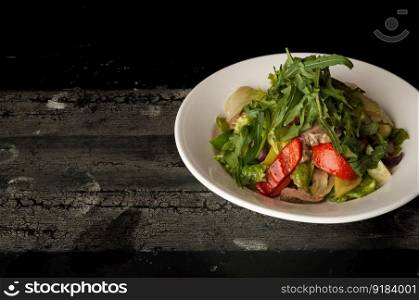 meat salad in a white plate on a wooden old surface. dish on a wooden surface