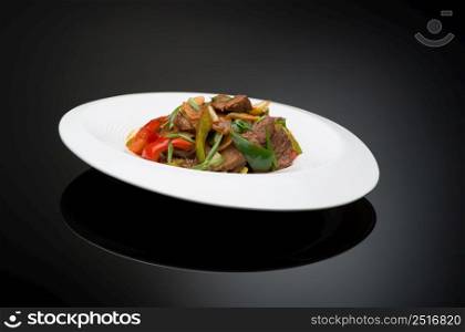 meat salad with bell pepper on a black background, isolated. dish on black background
