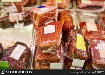 meat, sale and food concept - ham at grocery store stall