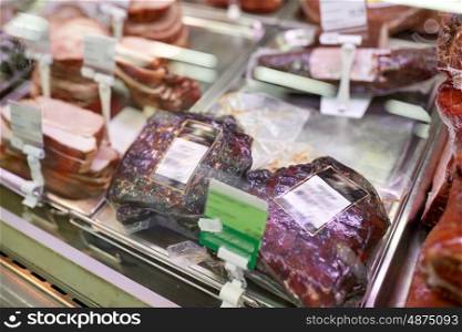 meat, sale and food concept - ham at grocery store stall