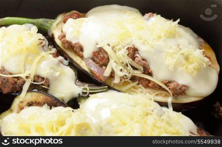 "Meat sauce-stuffed aubergines topped with bechamel sauce and cheese, ready for the oven. This is a Greek dish known as melitzanes papoutsaka, or "eggplant little-shoes"."