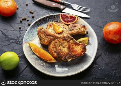 Meat steak, barbecue pork cutlet on the bone fried in a citrus marinade.. Pork steak on the bone baked with citrus fruits.