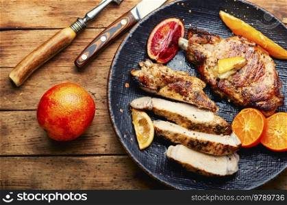 Meat steak cooked in oranges. Cutting in slices flank steak. Meat in citrus on old wooden table. Meat steak fried with citrus fruits