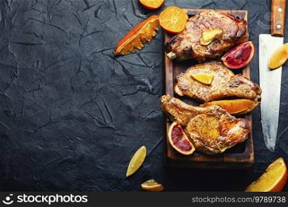 Meat steak cooked in oranges on a wooden cutting board. Meat in citrus marinade. Copy space. Meat steak fried with citrus,space for text