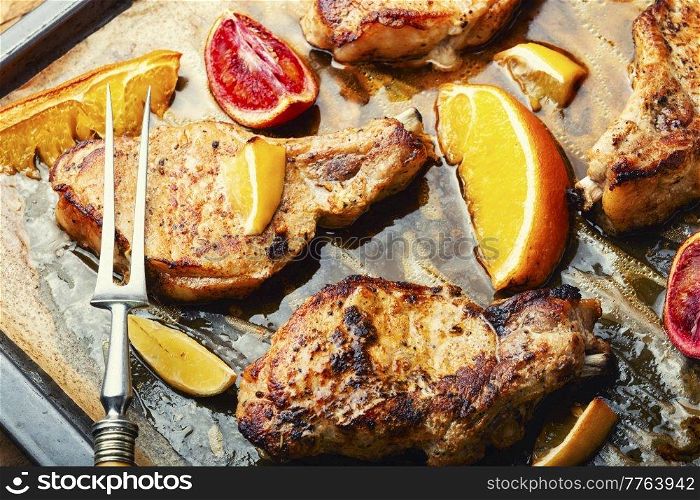 Meat steak, pork, cutlet on the bone fried in a citrus marinade. BBQ. Pork steak on the bone baked with citrus fruits.