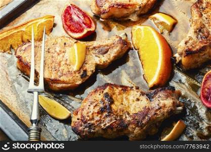 Meat steak, pork, cutlet on the bone fried in a citrus marinade. BBQ. Pork steak on the bone baked with citrus fruits.