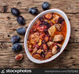 Meat stew with plums on rustic wooden background. Beef stew meat