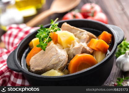 Meat stewed with carrots and potatoes in sauce on wooden rustic background