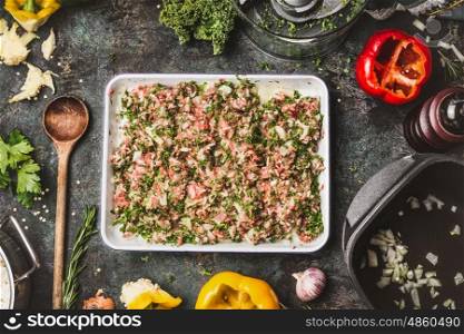 Meat stuffing with ground meat, rice and chopped kale for paprika filling on rustic kitchen table background with wooden cooking spoon, pot and vegetables ingredients, top view