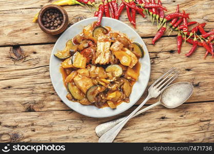 Meat with eggplant and pepper.Pork cooked with vegetables and hot spices.Meat stew with vegetable on rustic wooden table. Stewed meat with eggplant