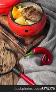meat with orange sauce. baked meat with orange sauce in a rustic iron pot