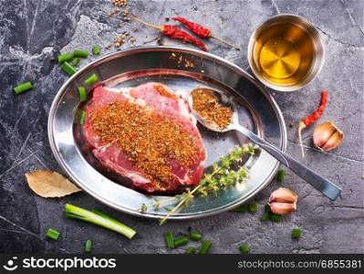 meat with spice on metal plate and on a table