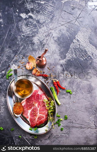 meat with spice on metal plate and on a table