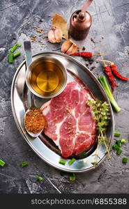 meat with spice on metal plate and on a table