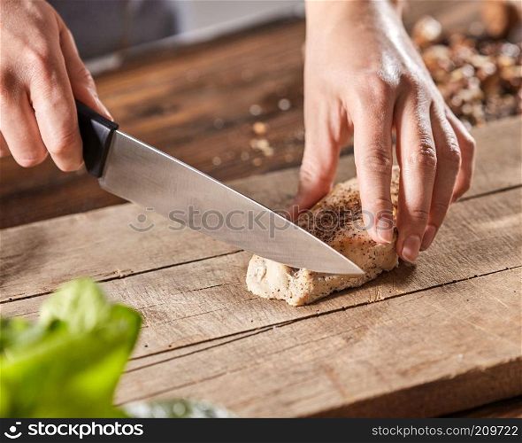 Meat with spice slice hands of cook woman on wooden kitchen board. Step by Step Cooking. A woman&rsquo;s hands are cutting meat on a wooden board on an old wooden table. Step-by-step cooking