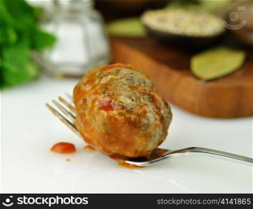 meatball with tomato sauce on a fork, close up
