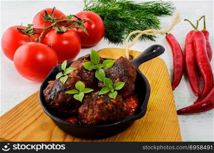 Meatballs with chili pepper and tomato served in cast iron skillet. Grilled spicy meatloaf. Barbecue meatballs. . Meatballs with chili pepper and tomato served in cast iron skill