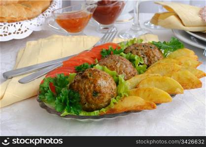 Meatballs with greens on salad leaves with potatoes and tomatoes