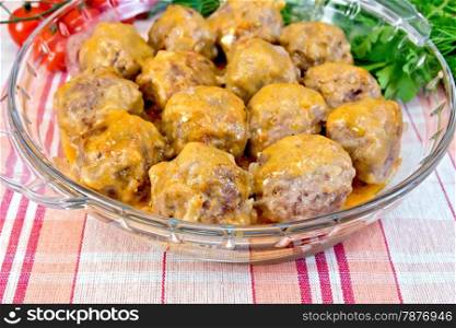 Meatballs with sauce in a glass pan, tomatoes, parsley on a linen tablecloth background