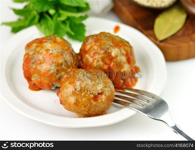 meatballs with tomato sauce on a white plate with fork