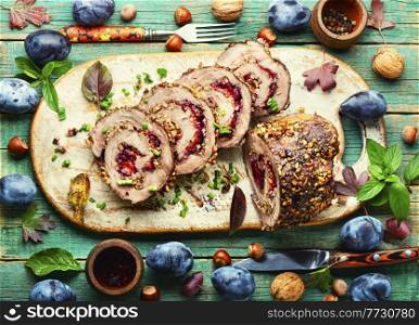 Meatloaf or meat roll baked with autumn plum on rustic wooden table. Festive meatloaf baked with plum