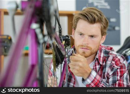 mechanic adjusting bicycle gear on wheel in workshop