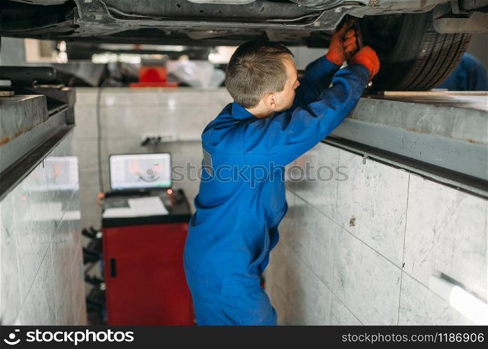 Mechanic adjusts the wheel angles on stand in auto-service. Computer diagnostic of car suspension, collapse of convergence. Mechanic adjusts the wheel angles on stand