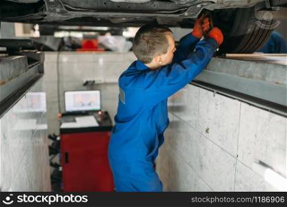 Mechanic adjusts the wheel angles on stand in auto-service. Computer diagnostic of car suspension, collapse of convergence. Mechanic adjusts the wheel angles on stand