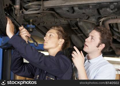 Mechanic And Apprentice Working On Car Together