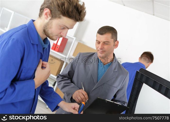 mechanic and apprentice working on car with computer