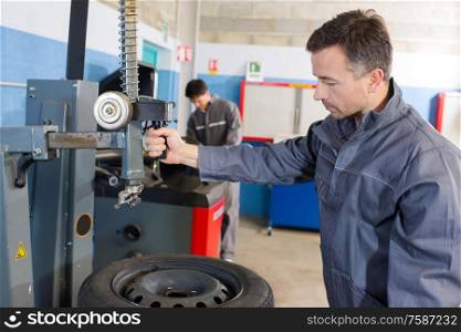 mechanic balancing wheel with machine at garage