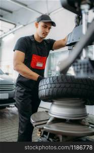Mechanic change tire, repairing service. Man repairs car tyre in garage, professional automobile inspection in workshop. Mechanic change tire, repairing service