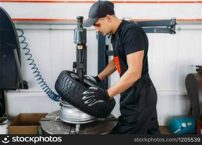 Mechanic change tire, repairing service. Man repairs car tyre in garage, professional automobile inspection in the workshop. Mechanic change tire, repairing service