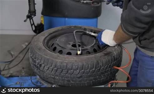 Mechanic checking the tire pressure after putting tire on rim