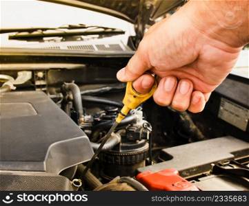 Mechanic hand pulling up oil dipstick of the car engine for checking oil level