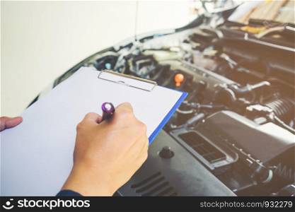 mechanic holding a clipboard of service order working in garage. Repair service.
