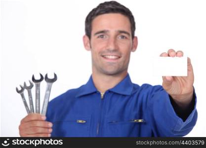 Mechanic holding selection of spanners and business card