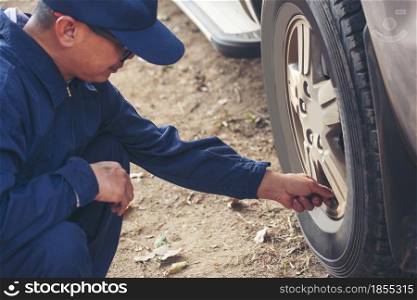 Mechanic man hands checking car tires outdoor on site service auto garage for automotive mobile center services. Technician workshop repair checking tyres car motor vehicles service mechanical hands