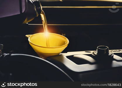 Mechanic man pouring lubricant oil to car engine in the repair garage