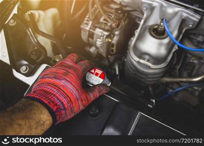Mechanic man with red glove is opening radiator cap of a car,Automotive maintenance concept.