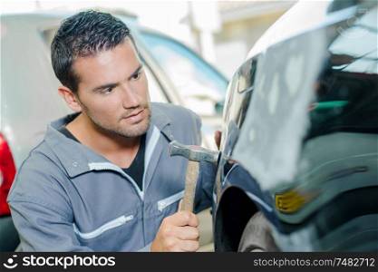 Mechanic panel beating a car