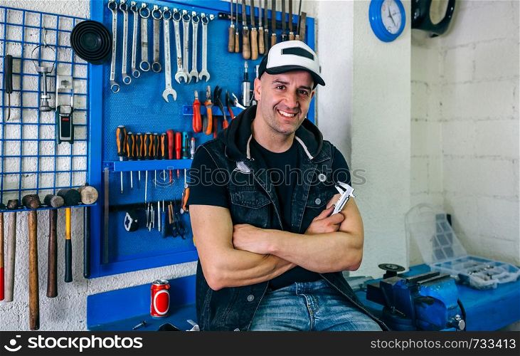 Mechanic posing with a customized motorcycle in his workshop. Mechanic posing with a motorcycle