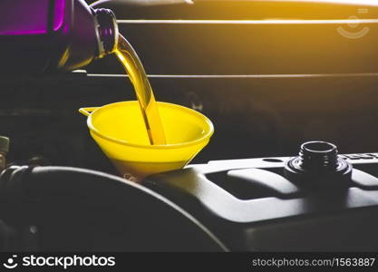 Mechanic pouring engine oil to car engine