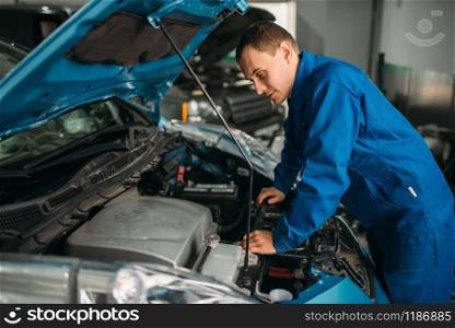 Mechanic repairs car engine, motor diagnostic. Car with opened hood, auto-service. Mechanic repairs car engine, motor diagnostic