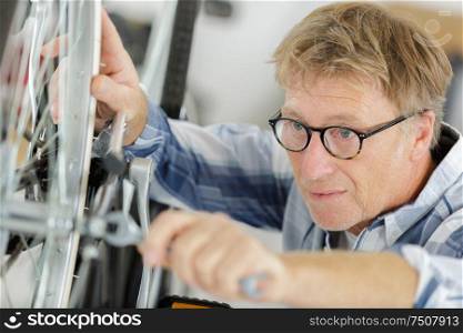 mechanic setting up chain on bicycle in workshop