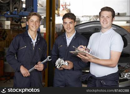 Mechanic Teaching Trainees In Garage Workshop